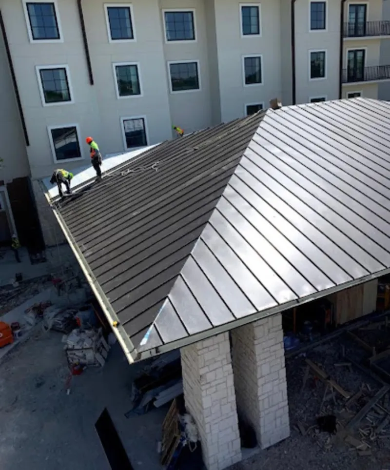 Crew installing standing seam metal roof panels on a commercial project in Falls Church